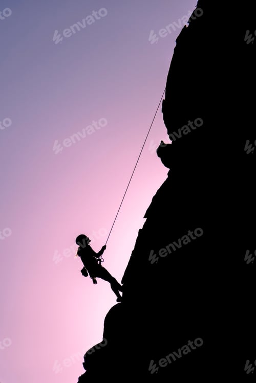 Preview: Vertical shot of a person silhouette climbing on a cliff