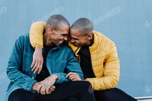 Preview: African American twin brothers embracing each other, wearing blue and yellow outfit