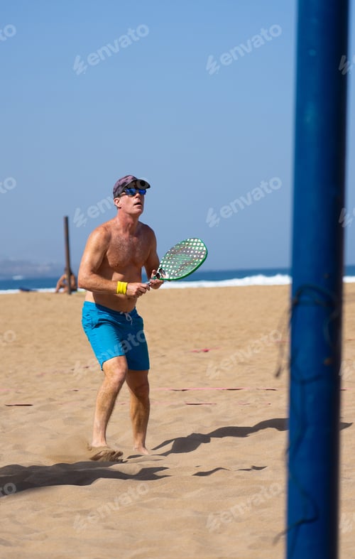 Preview: Man playing beach tennis on the beach in summer on a sunny day