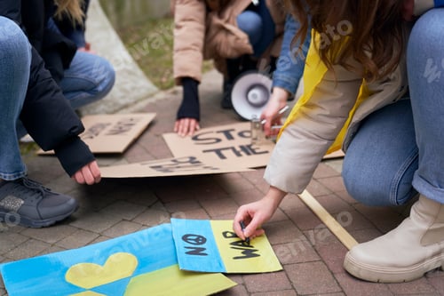 Preview: Group of young caucasian people preparing cardboard banners for manifest against Ukrainian war