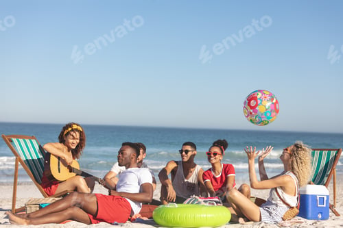 Preview: Front view of group of happy diverse friends having fun together on the beach