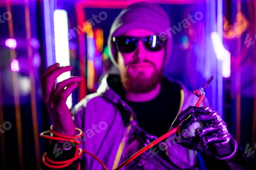 Preview: handsome young man with metal bionics prosthetic arm wrapped on wire in neon background space