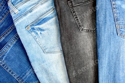 Preview: Variety of comfortable casual trousers, top view. Denim texture background.