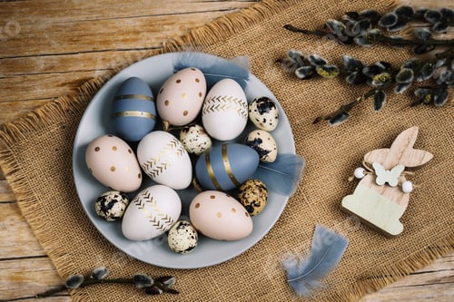 Preview: Gray plate with painted Easter eggs and willow branches on a wooden table. Easter greeting card.