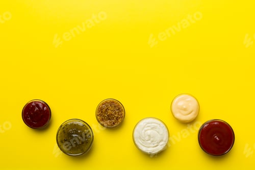 Preview: Different types of sauces in bowls on a colored Board . Top view. various sauces copy space