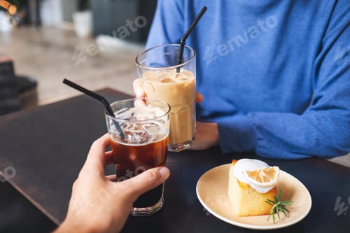 Preview: A couple people clinking coffee glasses together with lemon cake on the table in cafe