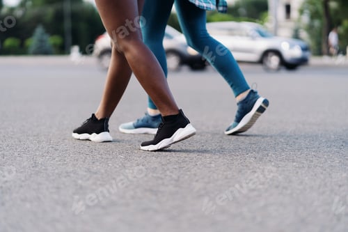 Preview: Two multiethnic girls legs jogging through the city streets, outdoor communicating