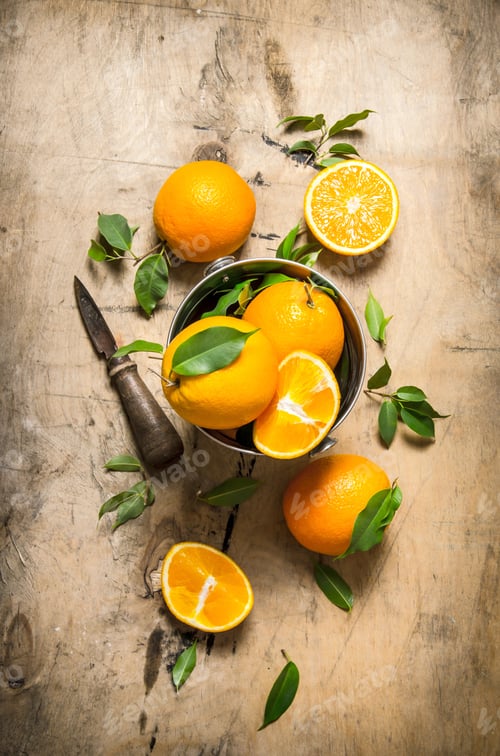 Preview: Fresh oranges with leaves in a bucket and a knife .