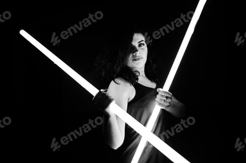 Preview: Curly brunette plus size model with two long led lamp at black room.