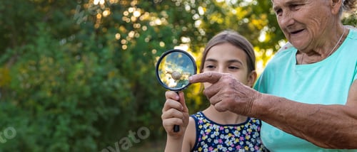 Preview: Grandmother and child are studying the snail in the park. Selective focus.