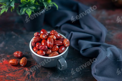 Preview: Close up view of fresh raw silverberry fruits inside and outside of a gray cup and flower pot on mix