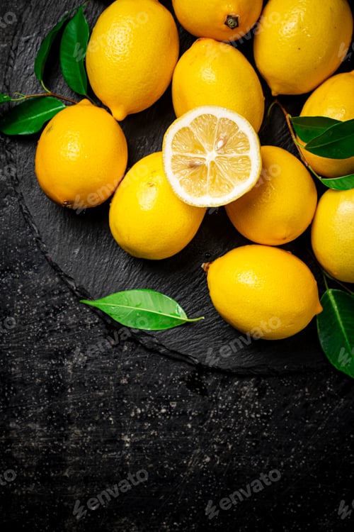 Preview: Juicy lemons with leaves on a stone board.