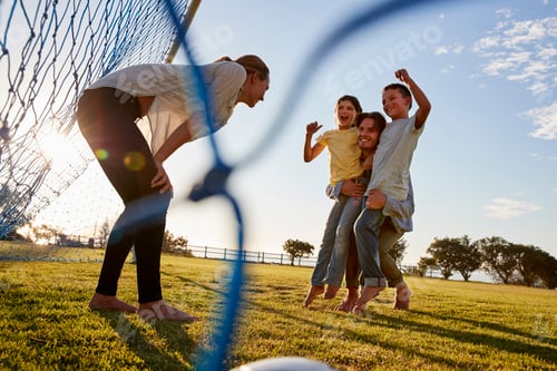 Preview: Dad lifts his son and daughter during a family football game