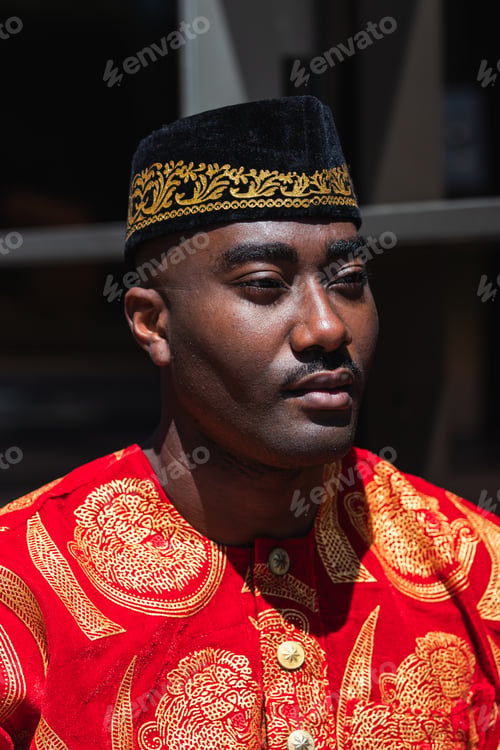 Preview: Thoughtful black man in traditional clothes and headdress near building