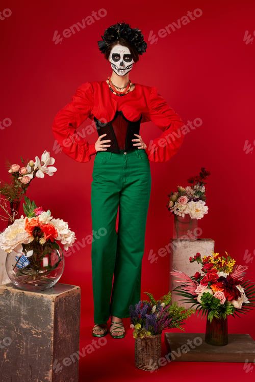 Preview: woman in sugar skull makeup near traditional dia de los muertos ofrenda with bright flowers on red