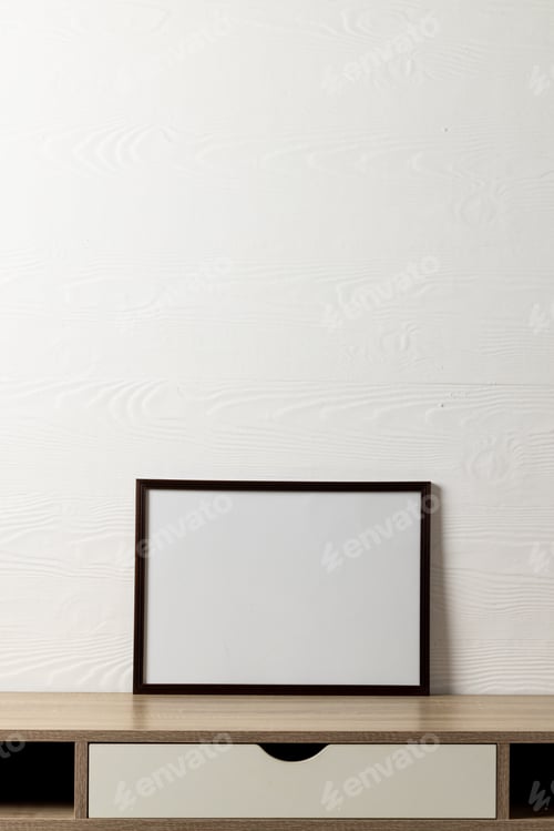 Preview: Black empty frame with copy space on table against white wall