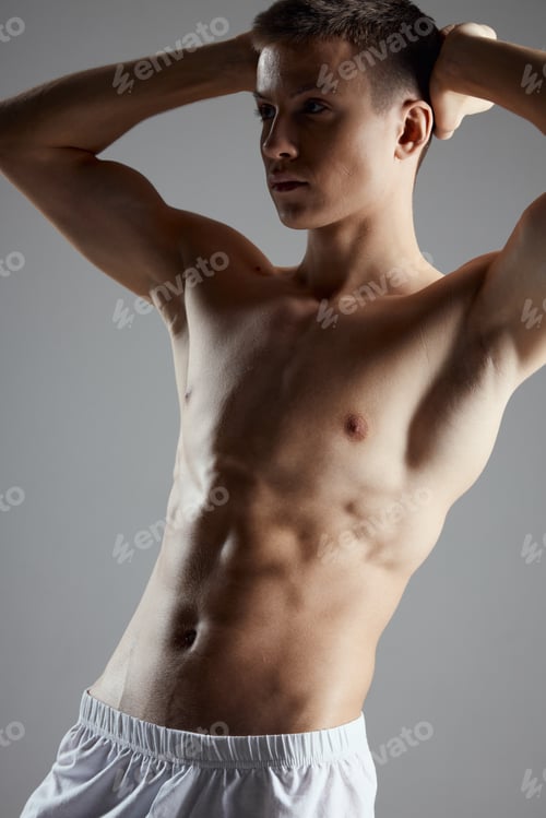 Preview: a pumped-up athlete with cubes on his stomach holds his hands behind his head
