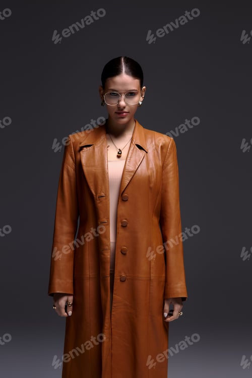 Preview: Stylish young woman showcases fashion in a leather coat and glasses
