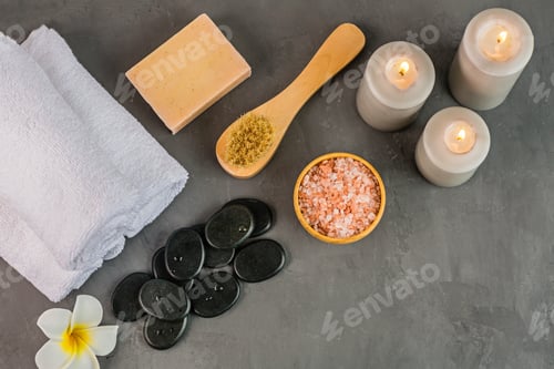 Preview: Flat lay of set for massage with hot stones, sea salt, aroma candles, brush and towels on gray