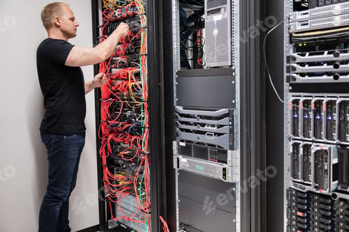 Preview: IT Technician Checking With Network Cables Connected To Servers