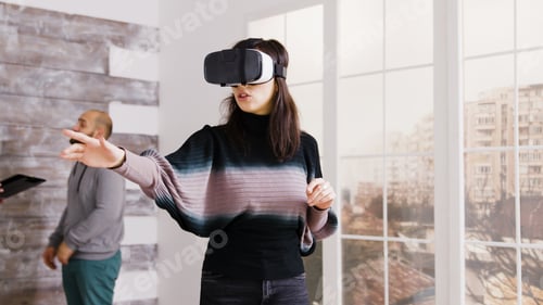 Preview: Female architect using virtual reality goggles in empty apartment