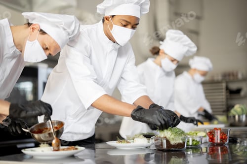 Preview: Group of cooks finishing main courses while working together in the kitchen