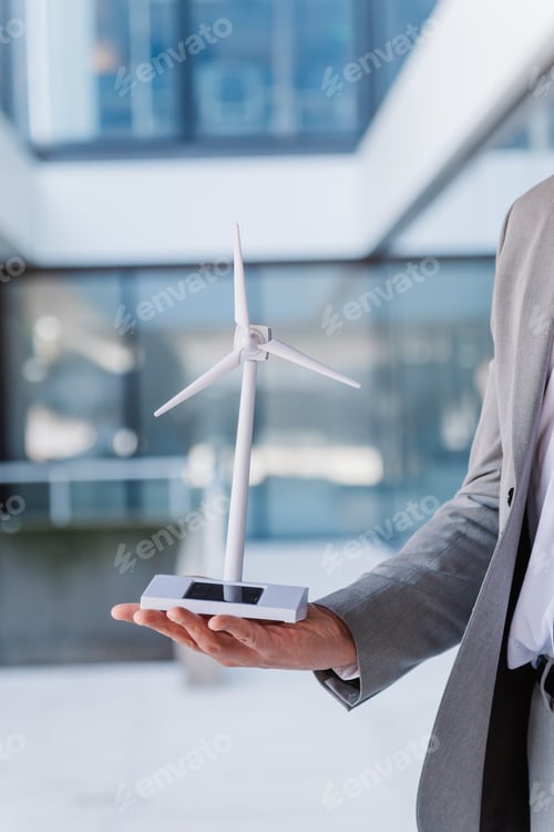 Businessman presenting compact renewable energy model, showcasing sustainable technology
