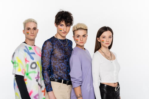 Preview: young friends with lgbtq flags on faces looking at camera isolated on grey