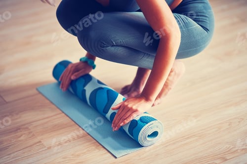 Preview: Woman Rolling Up a Blue Exercise Mat