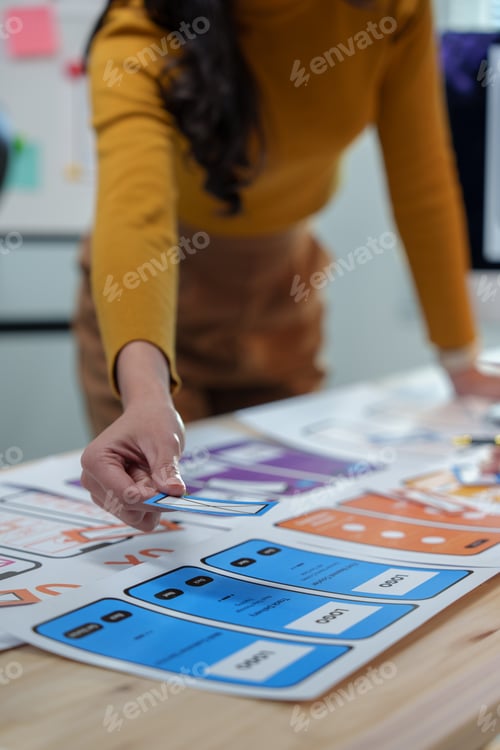 Preview: Female ux designer positioning paper prototypes on a large sheet of paper, planning user interface a