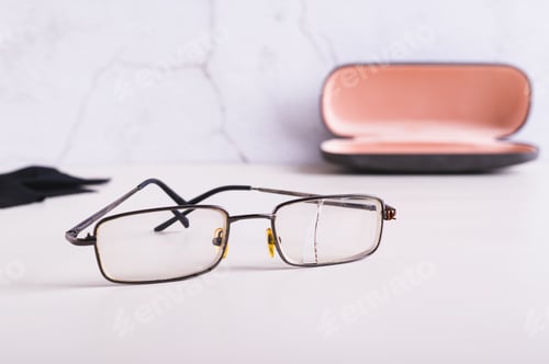Preview: Old broken broken glasses on the table against the background of an open hard case