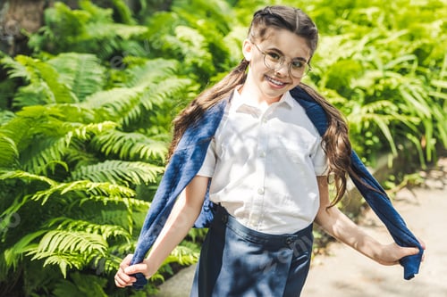 Preview: happy schoolgirl in white shirt and jumper over shoulders