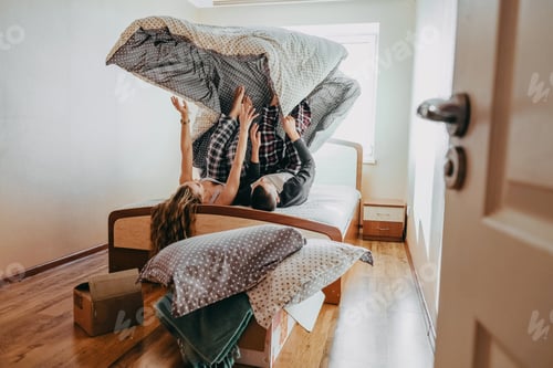 Preview: Happy young couple is having fun in bed in new empty home. Passionate beautiful couple in bedroom