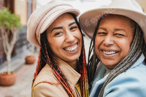 Preview: Happy african mother and daughter having fun hugging each other outdoor during winter time