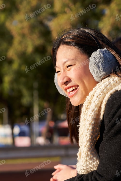 Preview: Young woman leaning on a bridge looking away, enjoying the view and smiling.