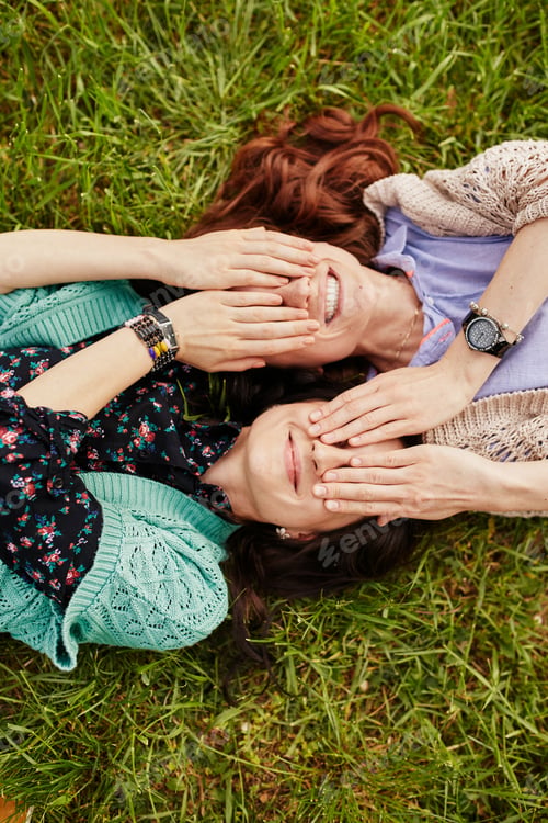 Preview: Two cheerful sisters lying on the grass
