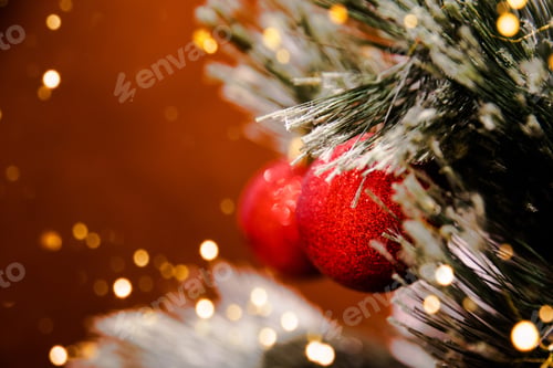 Preview: Red shiny glittering ball on Christmas tree with blurred lights.