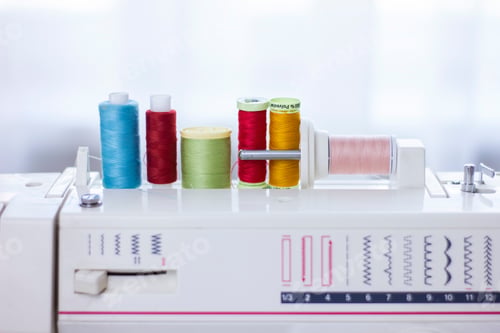 Preview: Closeup colorful thread spools on sewing machine.
