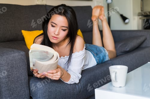 Preview: Young Woman Relaxing on Couch While Reading Book