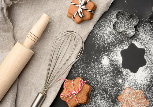 Preview: Star shaped baked gingerbread cookies sprinkled with powdered sugar on a black table