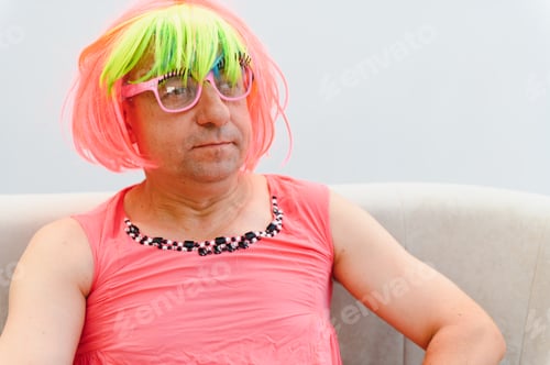 Preview: Man wearing pink wig and dress sitting on sofa