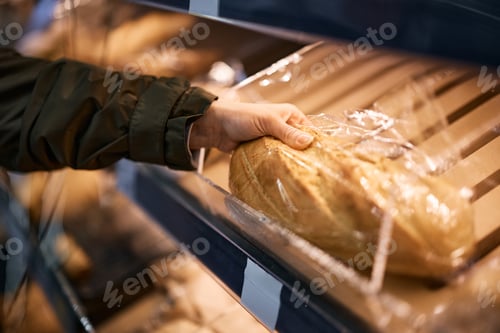 Preview: Close-up of woman taking loaf of bread while buying in supermarket.