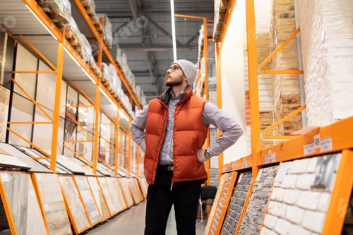 Preview: a buyer in a store of finishing materials examines shelves with artificial stone and porcelain