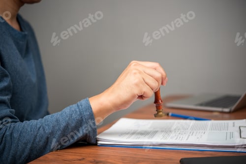 Preview: A hand stamps documents with a traditional wax seal for verification.