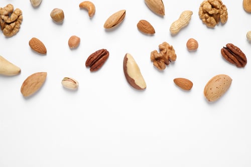 Preview: Different delicious nuts on white background, flat lay. Space for text