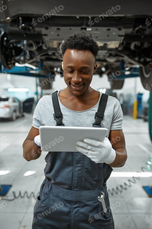 Preview: Worker using laptop, car on lift, auto service