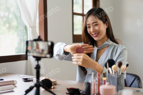 Preview: Beauty blogger holding blush on and showing product to reviewing cosmetic in makeup vlogger
