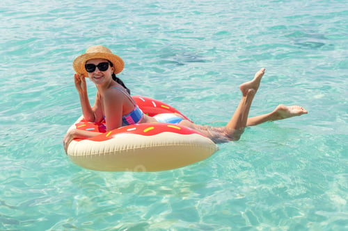 Preview: Beautiful woman with inflatable donut in sea