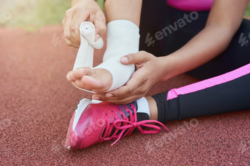 Preview: Afro American girl putting bandage on injured foot