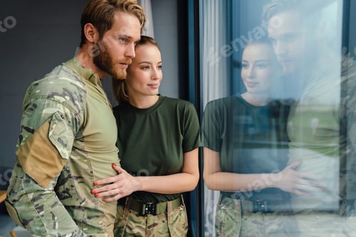Preview: Beautiful young couple hugging and looking out window indoors
